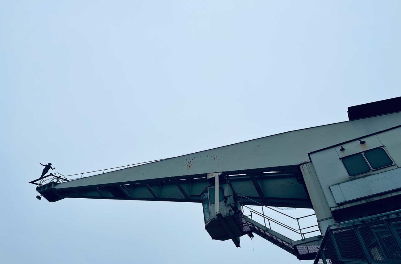 Industriekran am Kulturufer in Bingen. Auf der Spitze balanciert eine menschliche Gestalt.