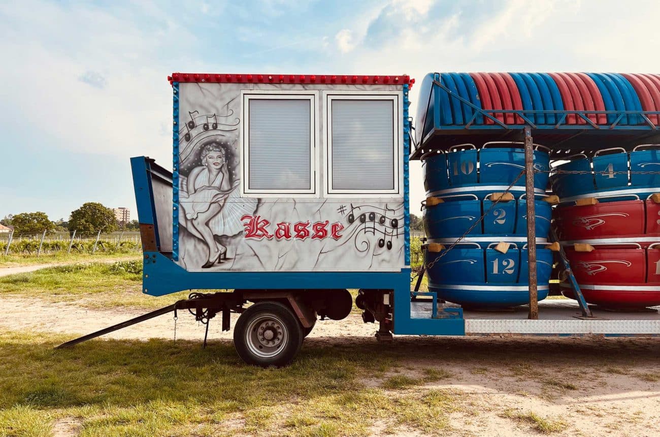 Eine Kirmeswagen (Kasse mit Riesenrad-Gondeln) steht einsam im Weinberg.