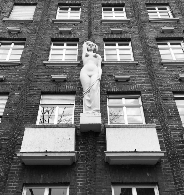 Nackte Frau an der Hauswand